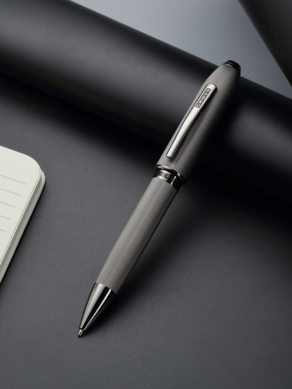 Silver pen on a dark surface with a notebook