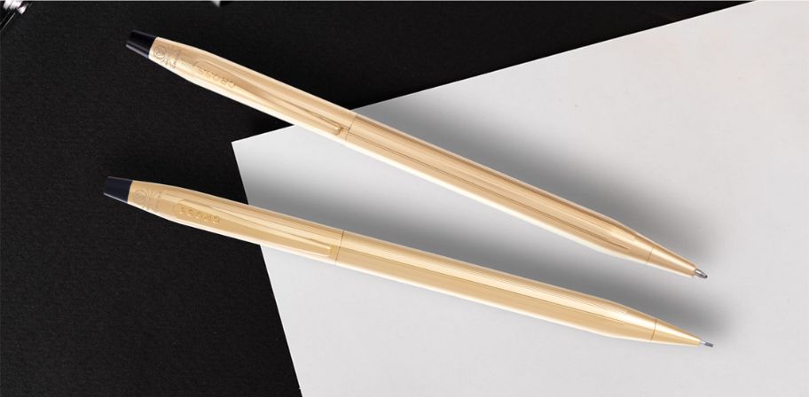 Two gold pencils on a black and white background